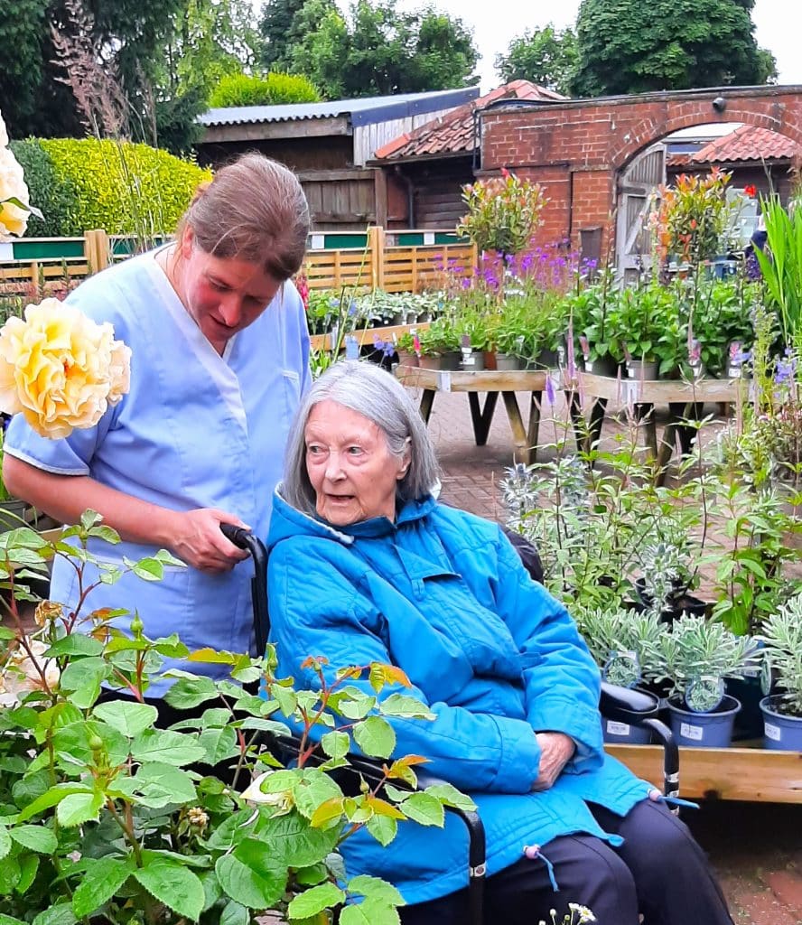 Carer showing lady in wheelchair plants at nursery